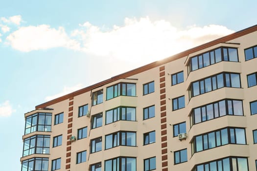 View of modern sand stucco facade with big bay window balcony and casement solid glass windows. New residential apartment condominium type. Block of flats. City real estate. Simple condo architecture