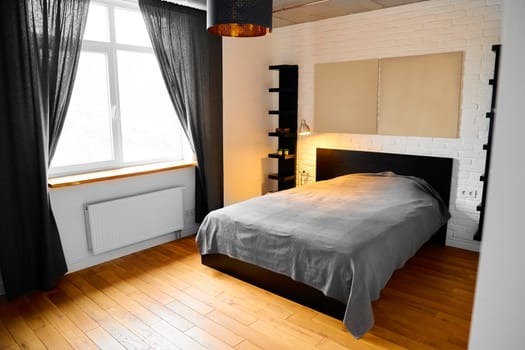 Simply bedroom in industrial design with white brick wall, concrete ceiling, wood floor, black cotton curtains and headboard full panel bed in modern style home. Common scandinavian clean look