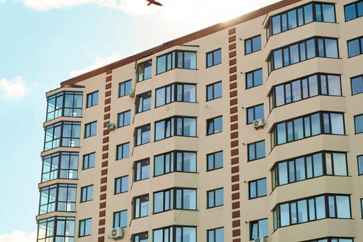 Block of flats. City real estate. Simple condo architecture. View of modern sand stucco facade with big bay window balcony and casement solid glass windows. New residential apartment condominium type