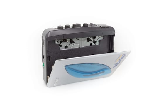 Sony Walkman. Vintage portable audio tape compact cassette player with headphones and cassette. Device on white background. Bergamo, ITALY - March 24, 2021.