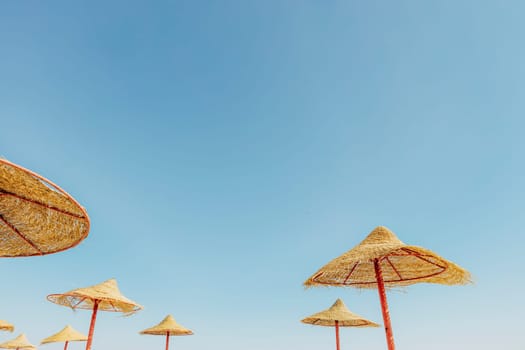 Looking up at wooden straw umbrella or thatched hut from below against beautiful cloudy blue sky view on tropical Egypt beach. Summer or winter holiday concept. Egyptian resort. High quality photo