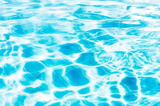 Vibrant blue white swimming pool ripped water surface with waves and nice sun sparkles. Conceptual abstract texture background. Travel or vacation summer concept. High quality photo