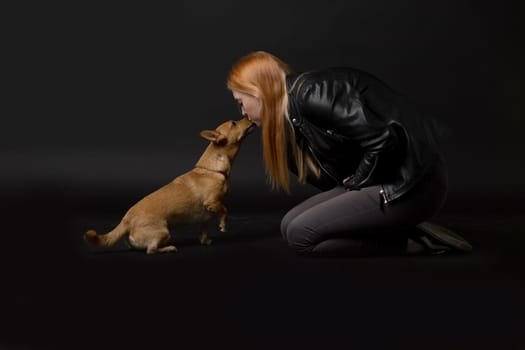 Studio portrait of beautiful young woman kissing her dog.