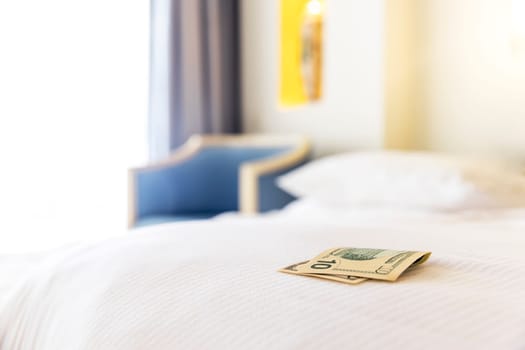 Traditional tips is laying on the corner of the bed in hotel room. Dollar or euro money tips to thank the room cleaner for good service. Grateful vacationers at the Egypt resort. High quality photo