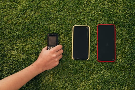 The Human Hand Picks an Old Phone That Lies Near New Smartphones.
