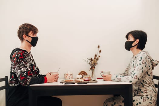 Girl and Guy Drinking Tea at Home in Masks.