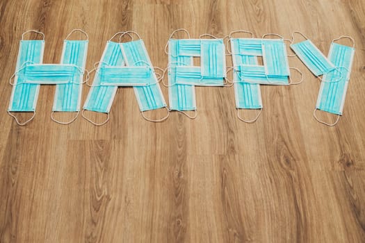Capital Letters Happy Composed of Medical Masks on a Brown Background
