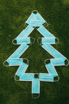 Christmas Tree Made of Medical Masks on a Green Background
