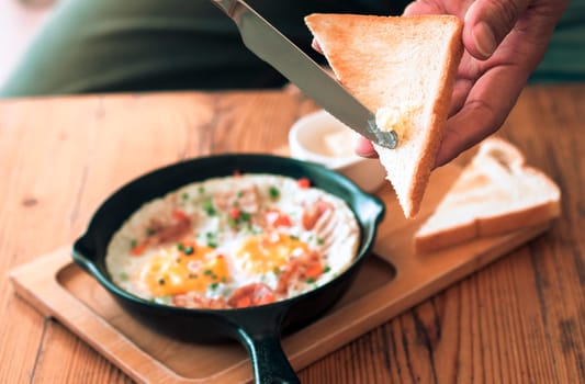 Man spreading butter on the bread with Pan Fried Egg with Toppings
