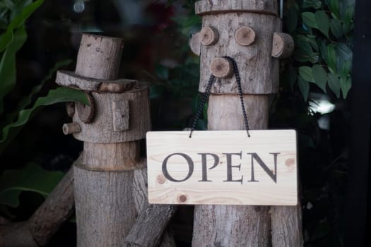 Open Sign Hanging on wooden doll in front of entrance door for decoration cafe restaurant.
