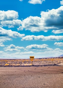 Directional sign in the desert with scenic blue sky and wide horizon. Concept for trip, freedom, holiday and transportation.