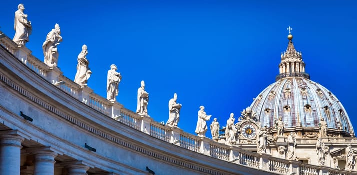 Statues of Catholic Saints. Decorations on Bernini colonnade, Saint Peter Cathedral, with the Cupola in background - Rome, Italy