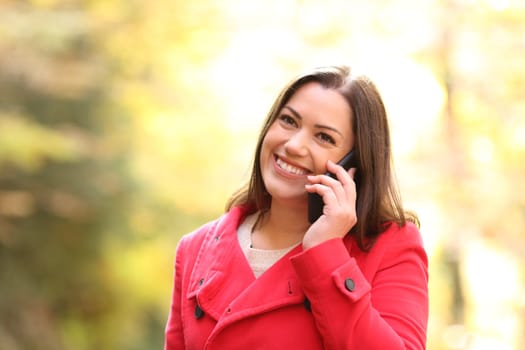 Happy woman in red talking on phone in winter