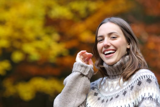 Happy woman looking at you in autumn in a park