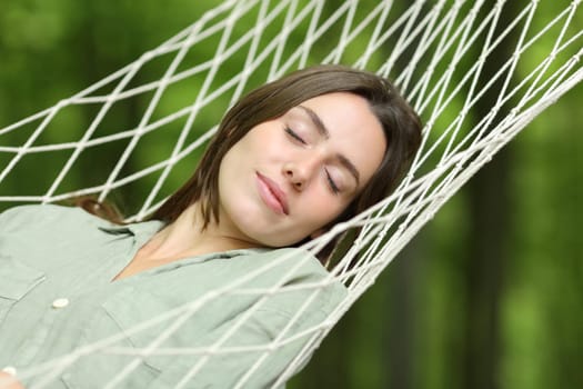 Woman sleeping lying on hammock in a forest
