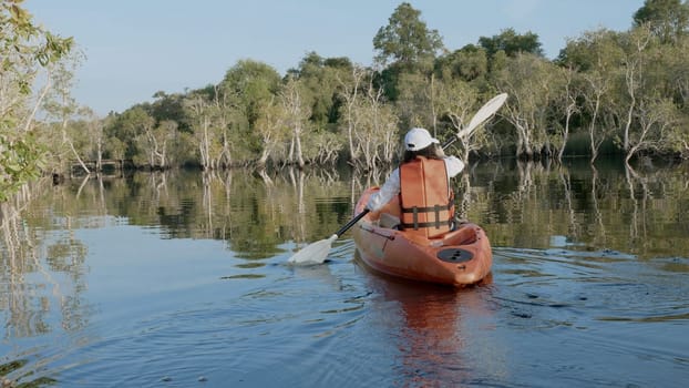Back young adult woman paddling kayaking canoe on a lake on summer day in rural landscape, adventure travel leisure enjoying concept, lifestyle sport vacation