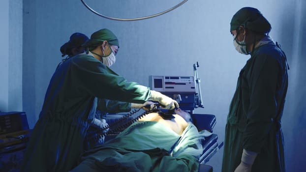 Defibrillation cardiac dysrhythmia, Surgical doctor team performing surgery patient on operating room in hospital, doctors use medical devices automated External Defibrillator to pump hearts patients