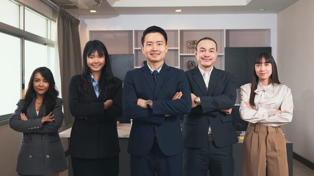 Successful group of business people smiling while standing with crossed arms in office, business team in formal suits they are folding their arms over the chest and looking at camera