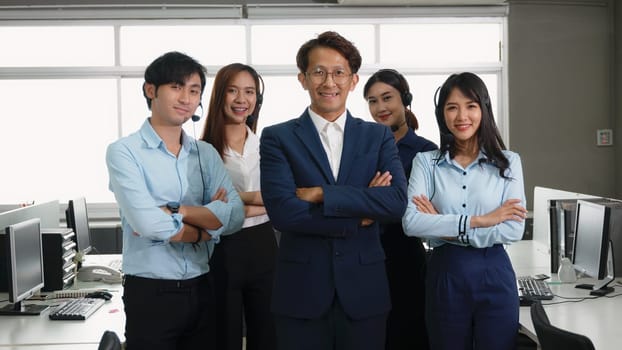 Businessman leader smiling in formal suit glasses standing smart with his arms crossed in an office workplace, portrait of happy young male boss manager or CEO look at camera