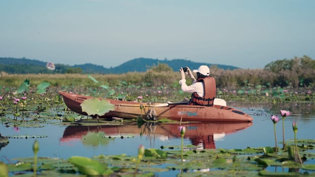 Young adult woman kayaking canoe boat on a lake she take photo natural scenery by smartphone on summer day, adventure travel leisure enjoying concept, lifestyle sport vacation