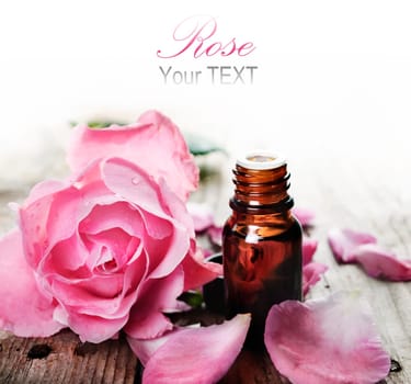 Essential oil with rose petals on wooden background