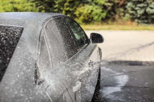 Car being washed at carwash. Focus only on flying drops of shampoo and foam for dynamic effect.