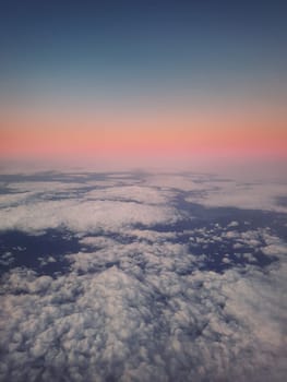 Sunset cloudscape, aerial view out of the plane window above the fluffy clouds. Tranquil sky evening scene, misty nebula. Air fresheners, celestial beauty, vertical background