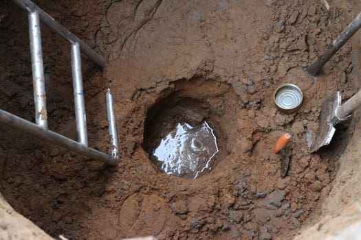 groundwater has appeared at the bottom of a deep round well with hand tools
