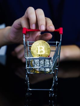 Close up business women holding shopping cart with  Bitcoin coin in black background