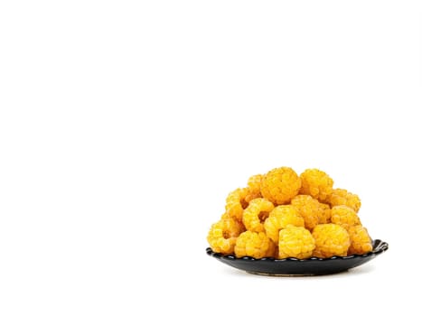 Berries of yellow raspberries in a black plate on a white background. Yellow raspberries. Fruit berries. Harvesting. Fruit dessert. Healthy eating. White background. Shop window.