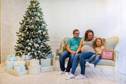 Family portrait near christmas tree. Pregnant woman.