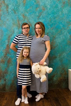 Family portrait with pregnant woman, girl and man in striped clothes.
