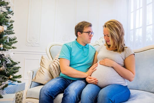 Family portrait near christmas tree. Pregnant woman.