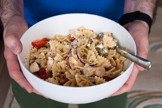 Step by step home cooking salad recepie. Close-up hands men hold a bowl with pasta salad