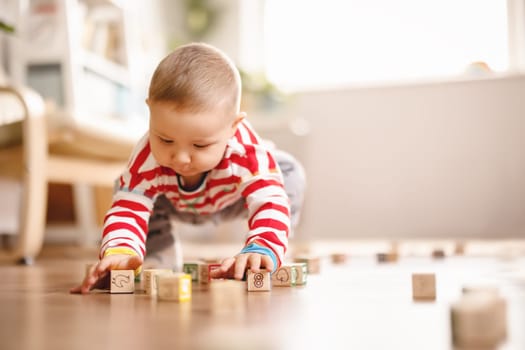 Little baby playing with toys on the floor indoors. Concept of the family relationship, studying and learning.