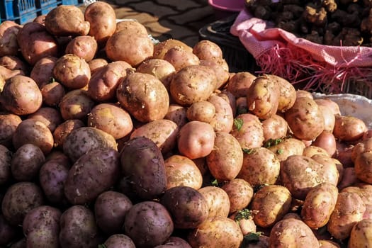 Sun shines on pile of potatoes displayed at street food market in Morocco.