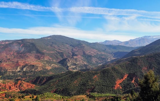 Typical Morocco landscape in area near Foret Toufliht park - red mountains with low green trees and bushes.