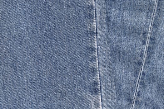 Denim background in blue fabric with faded. Blue discolored jeans close-up