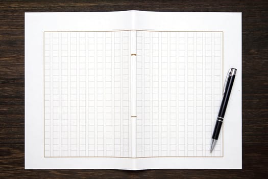 Japanese manuscript paper with ballpoint pen. Genko yoshi on wooden table