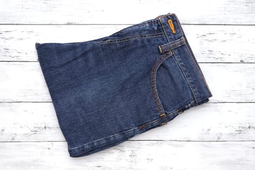 Folded blue jeans on white wooden background, denim folded on wooden background