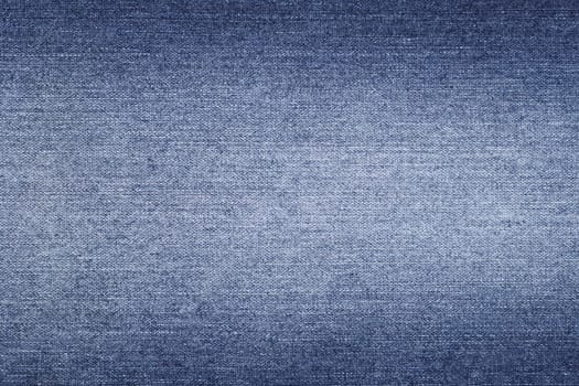 Denim background in blue fabric with faded. Blue discolored jeans close-up