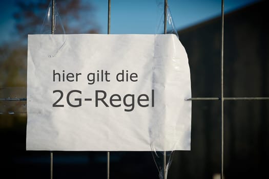 Sign on the fence of a venue with the inscription hier gilt die 2G-Regel (here applies the 2G rule). 2G means access only with a valid full corona virus Covid 19 vaccination or proof of recovery.