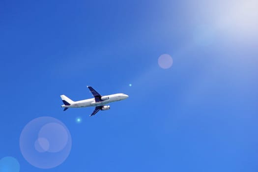 Plane flying high in blue sky with sunny rays. Air liner flying in blue sky. Airplane seen in heaven. Aerial panorama with aircraft in cloudless sky. Flying air liner. Passenger airliner in flight