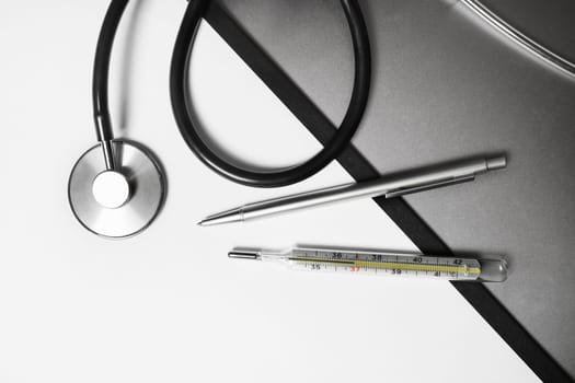 Medical stethoscope, thermometer and pen. Flat lay.