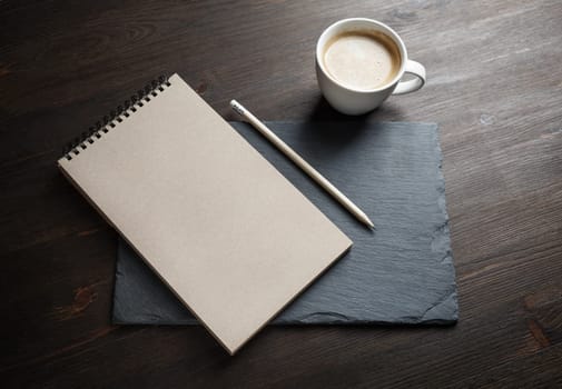 Blank kraft sketchbook, pencil and coffee cup on stone board. Responsive design mockup.