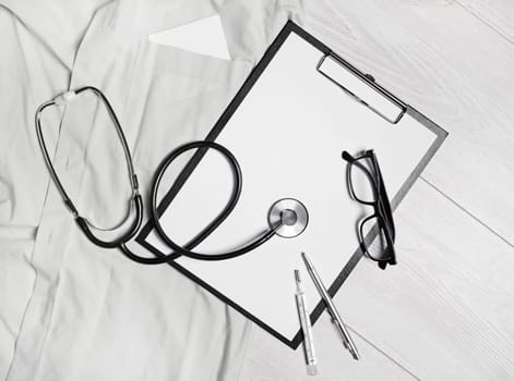 Medical still life. Blank clipboard, stethoscope, glasses, thermometer and pen. Flat lay.