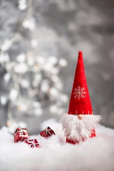 Christmas gnome greeting card with bokeh lights and snow, winter season, gift on the sledge