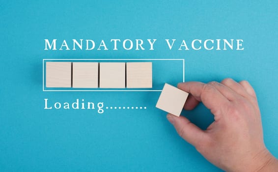 Mandatory vaccination is standing on a blue background, loading bar, hand puts last cube