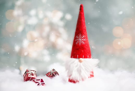 Christmas gnome greeting card with bokeh lights and snow, winter season, gift on the sledge