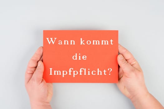 When does the mandatory vaccination comes is standing in german language on the red colored paper, covid-19